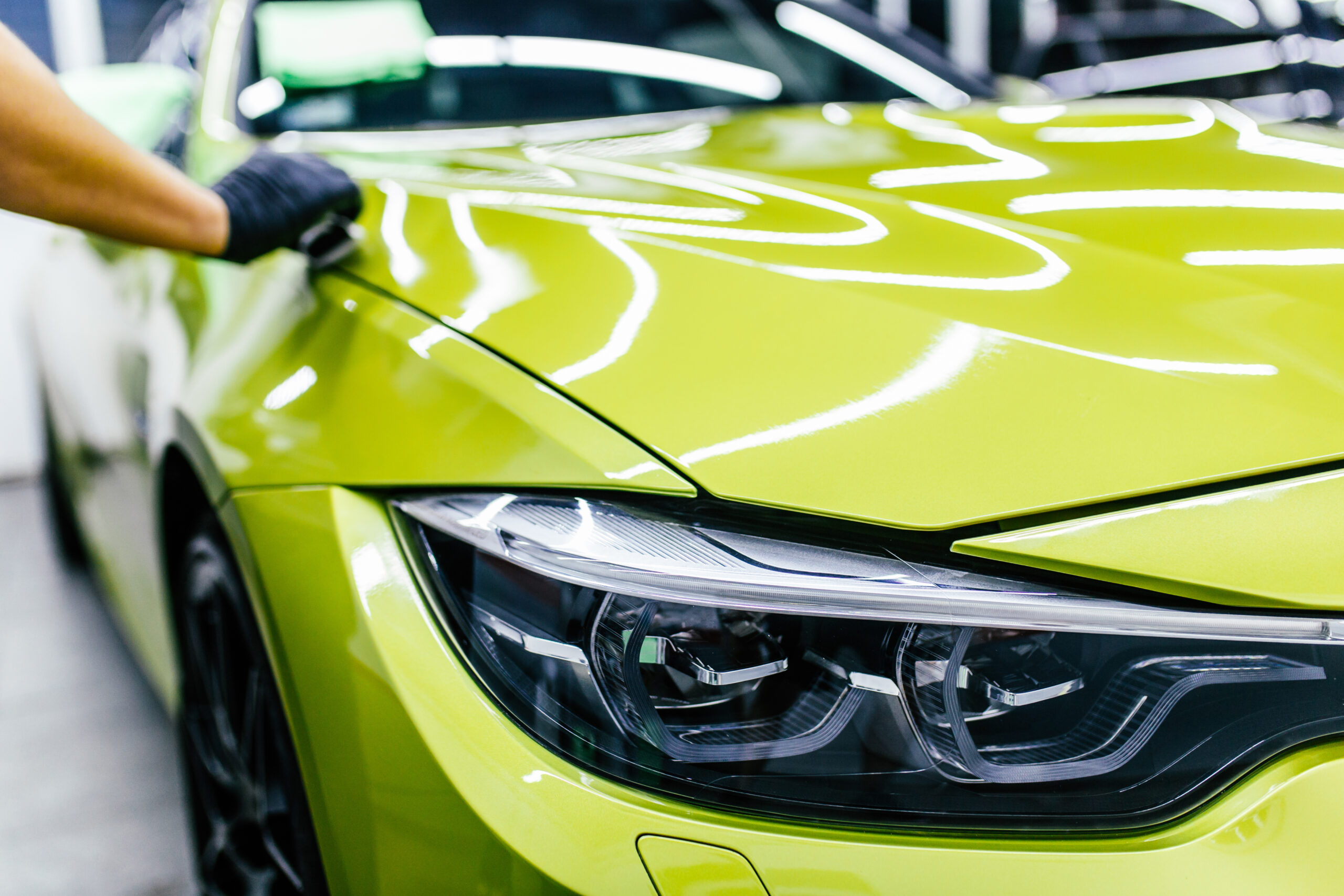 Detailer polishing high-gloss vehicle panel on dealership lot